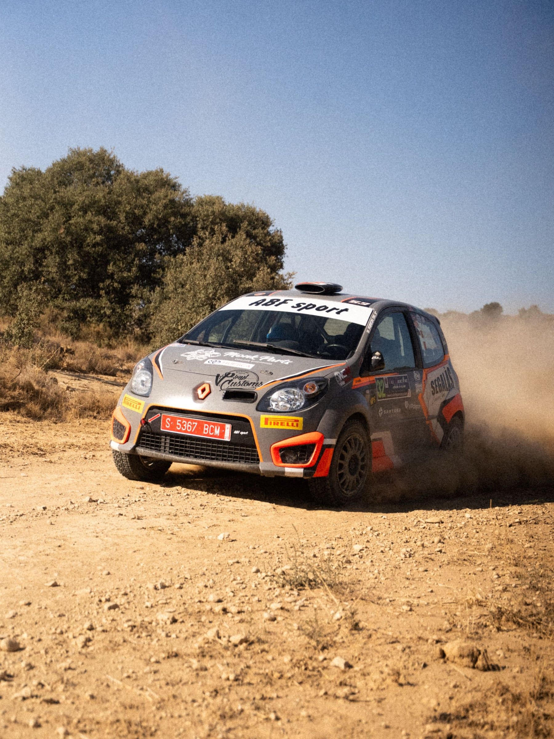 Renault Twingo naranja y gris saliendo de la curva