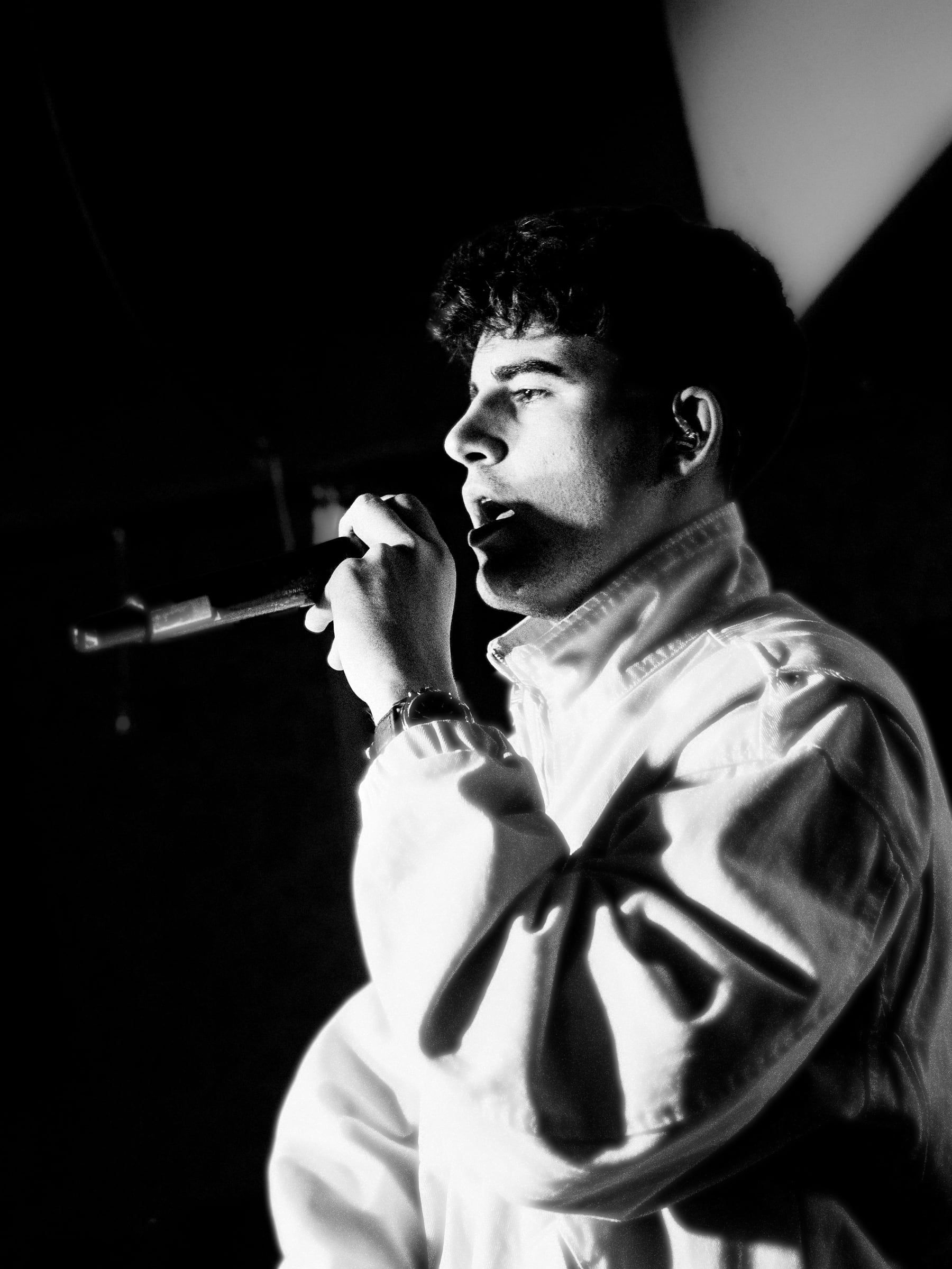 Artista en blanco y negro cantando con los ojos entrecerrados
