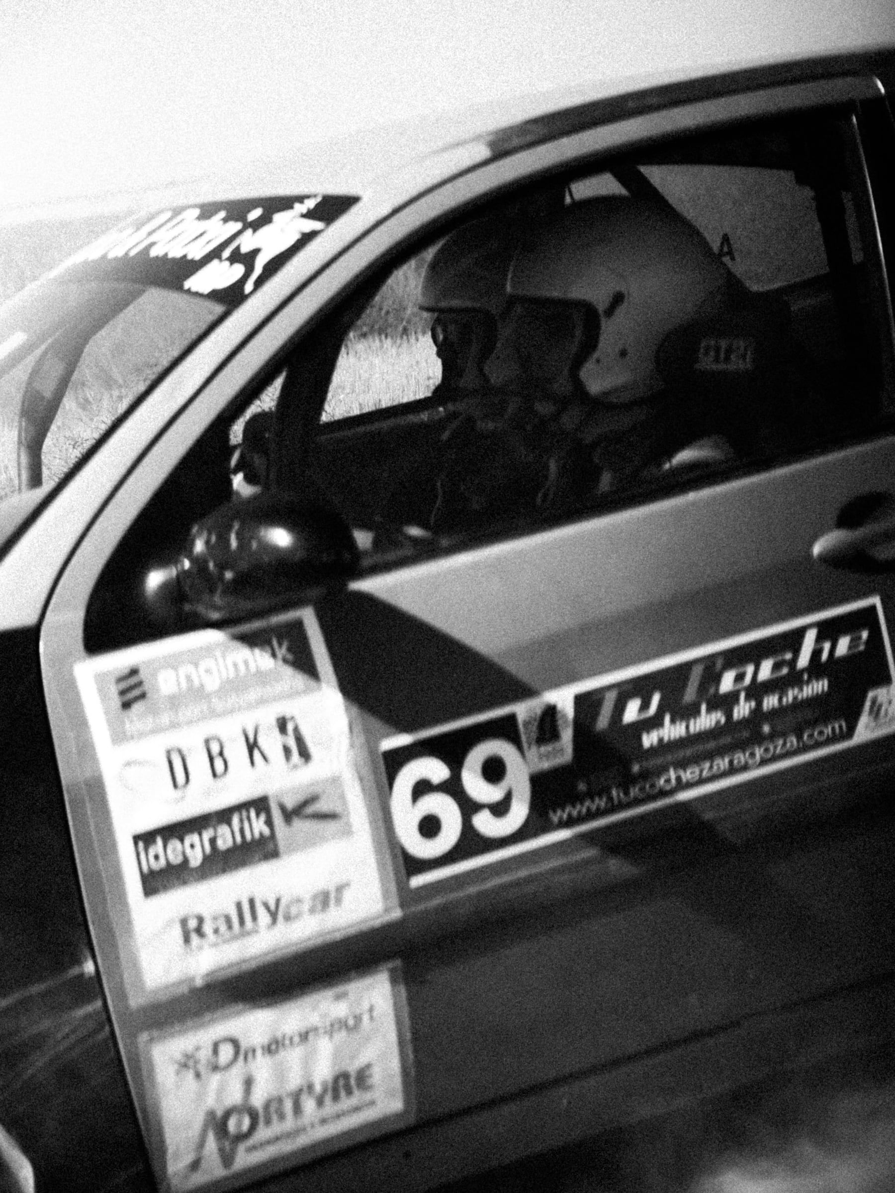 Piloto con casco tras la ventanilla del coche 69, en blanco y negro