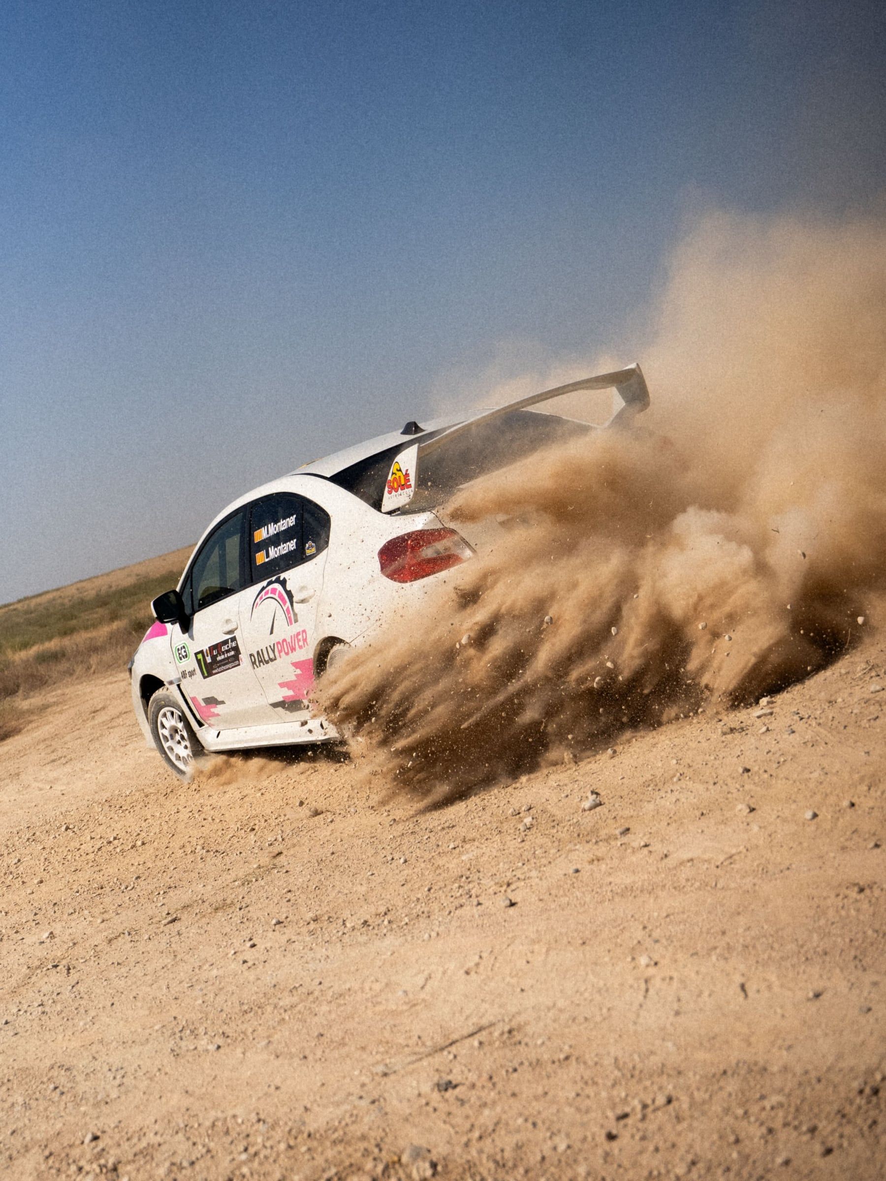 Coche blanco levantando una nube de tierra en la curva